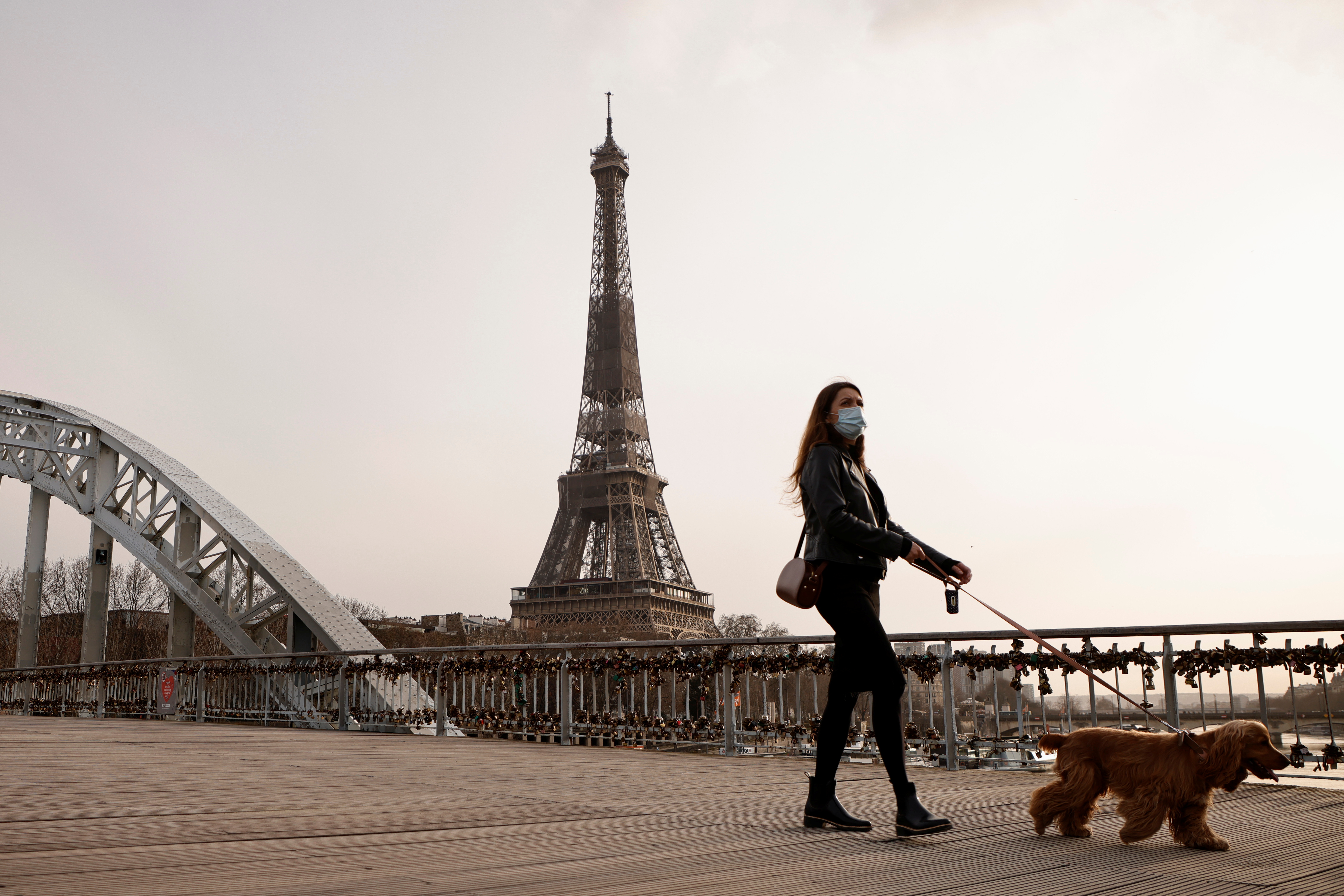 Una mujer pasea a su perro en París.