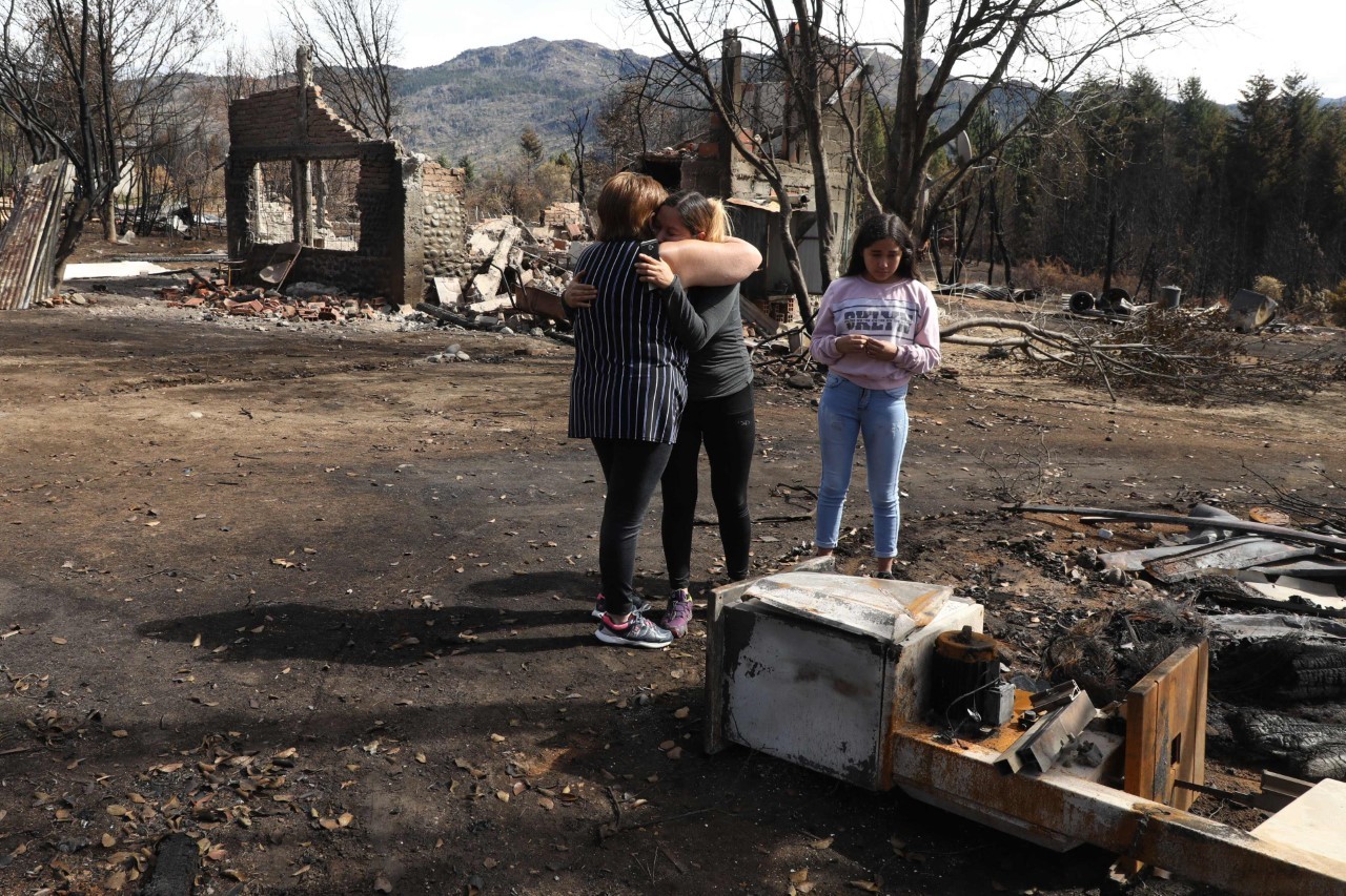 Dos mujeres se abrazan tras un incendio en Las Golondrinas town, en la provincia de Chubut