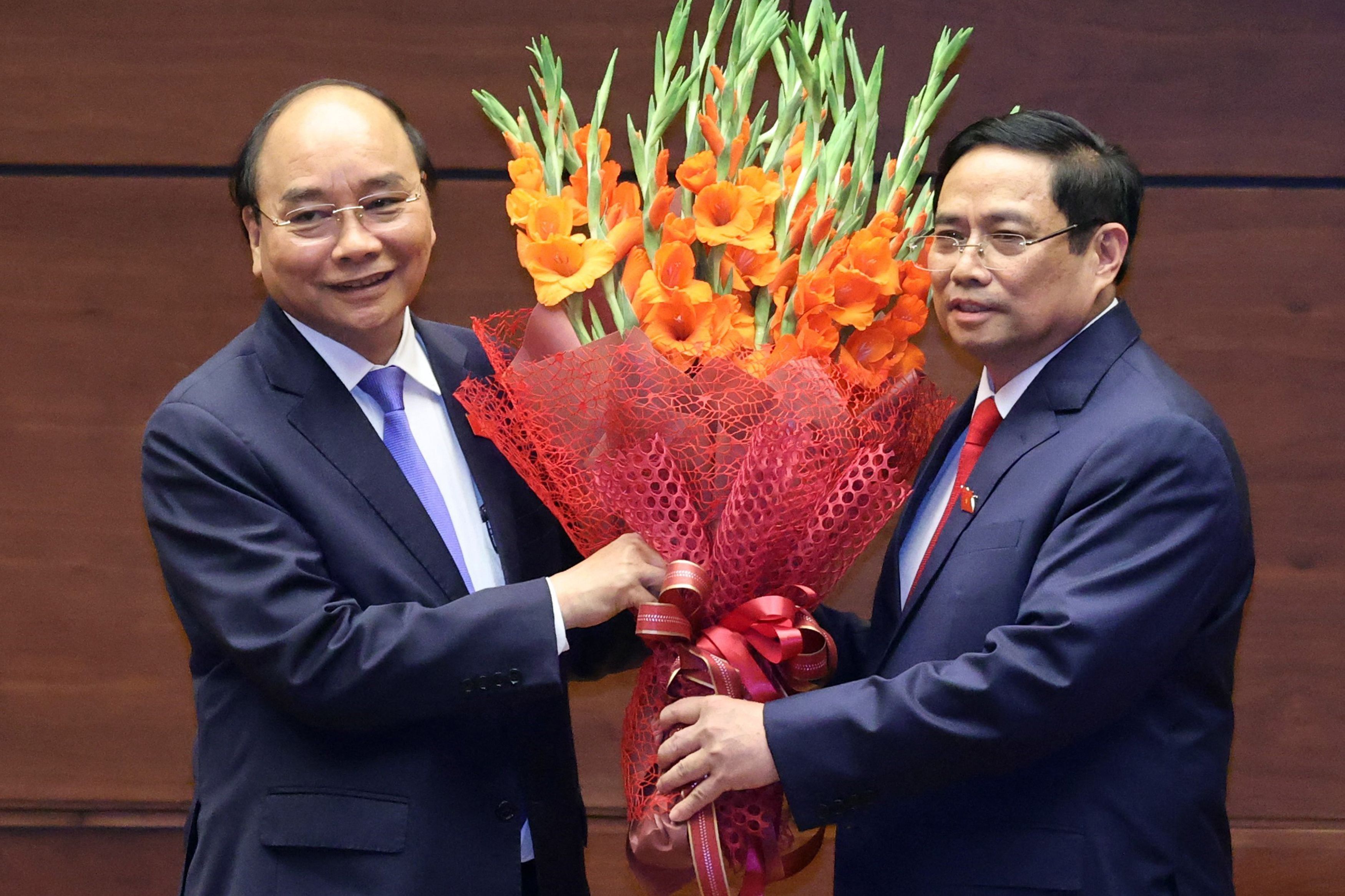 El 'premier' Pham Minh Chinh (dcha.) recibe un ramo de flores en Hanoi.
