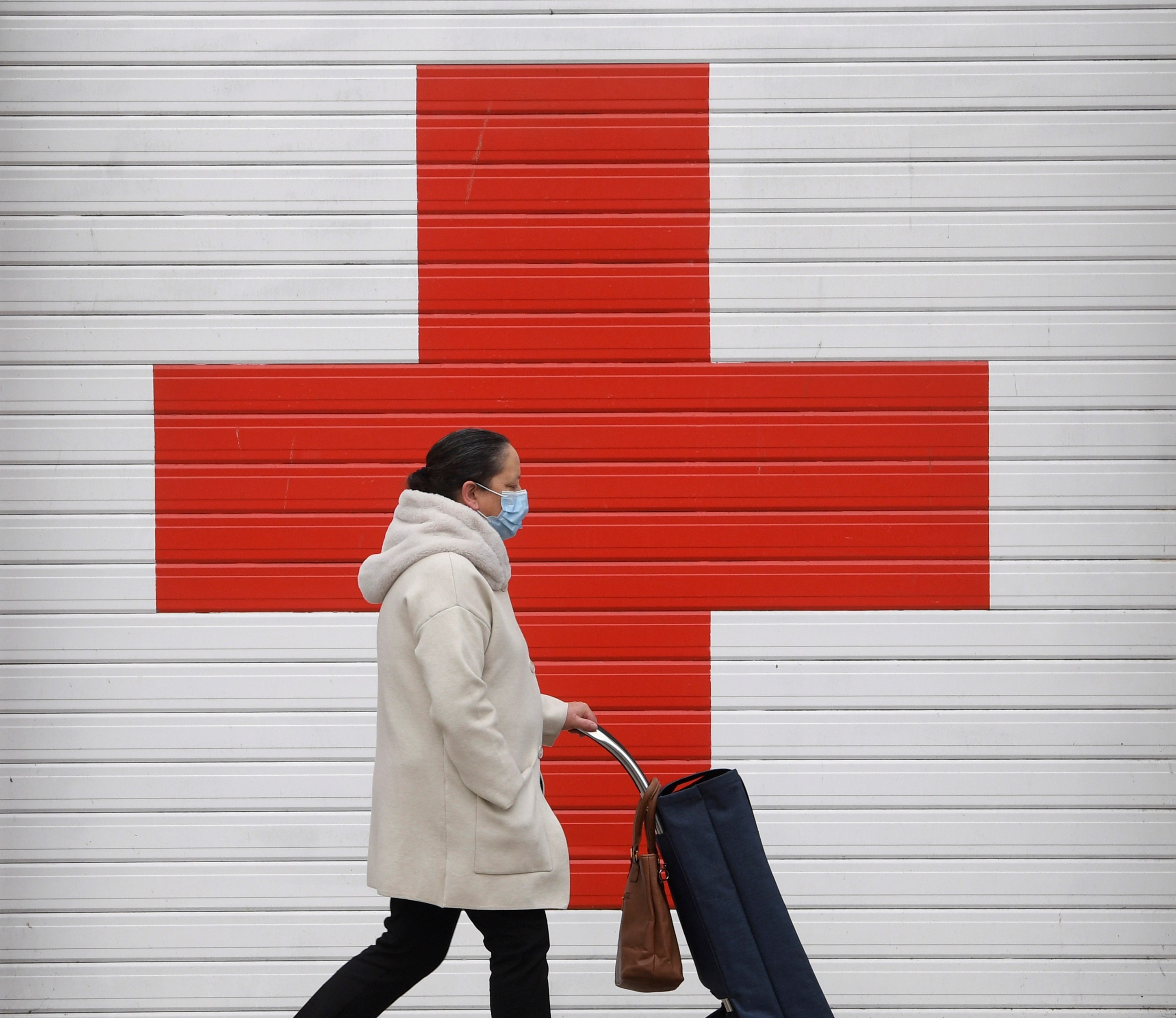 Una mujer camina con mascarilla ante la puerta de entrada de ambulancias del  Hospital de La Cruz Roja en Oviedo.