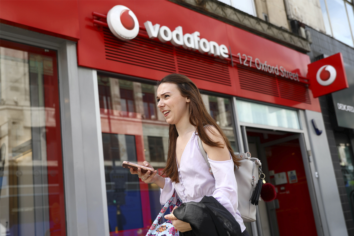 Una joven delante de una tienda de Vodafone.
