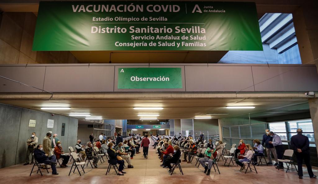 Decenas de personas esperan su turno para vacunarse este jueves en el centro instalado en el estadio de la Cartuja, en Sevilla.