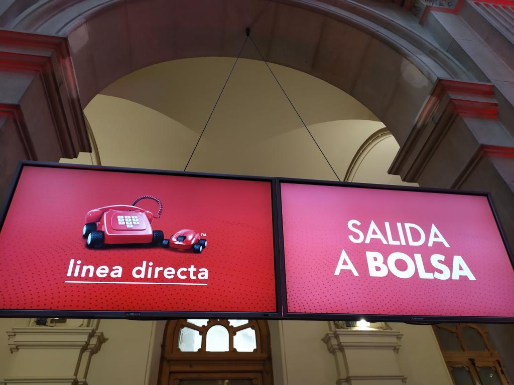 Dos pantallas anuncian el estreno de Lnea Directa en el Palacio de la Bolsa de Madrid.
