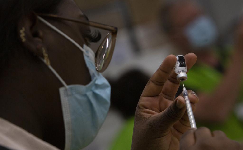 Una sanitaria llena una jeringa con un vial de la vacuna de Pfizer en Blgica.