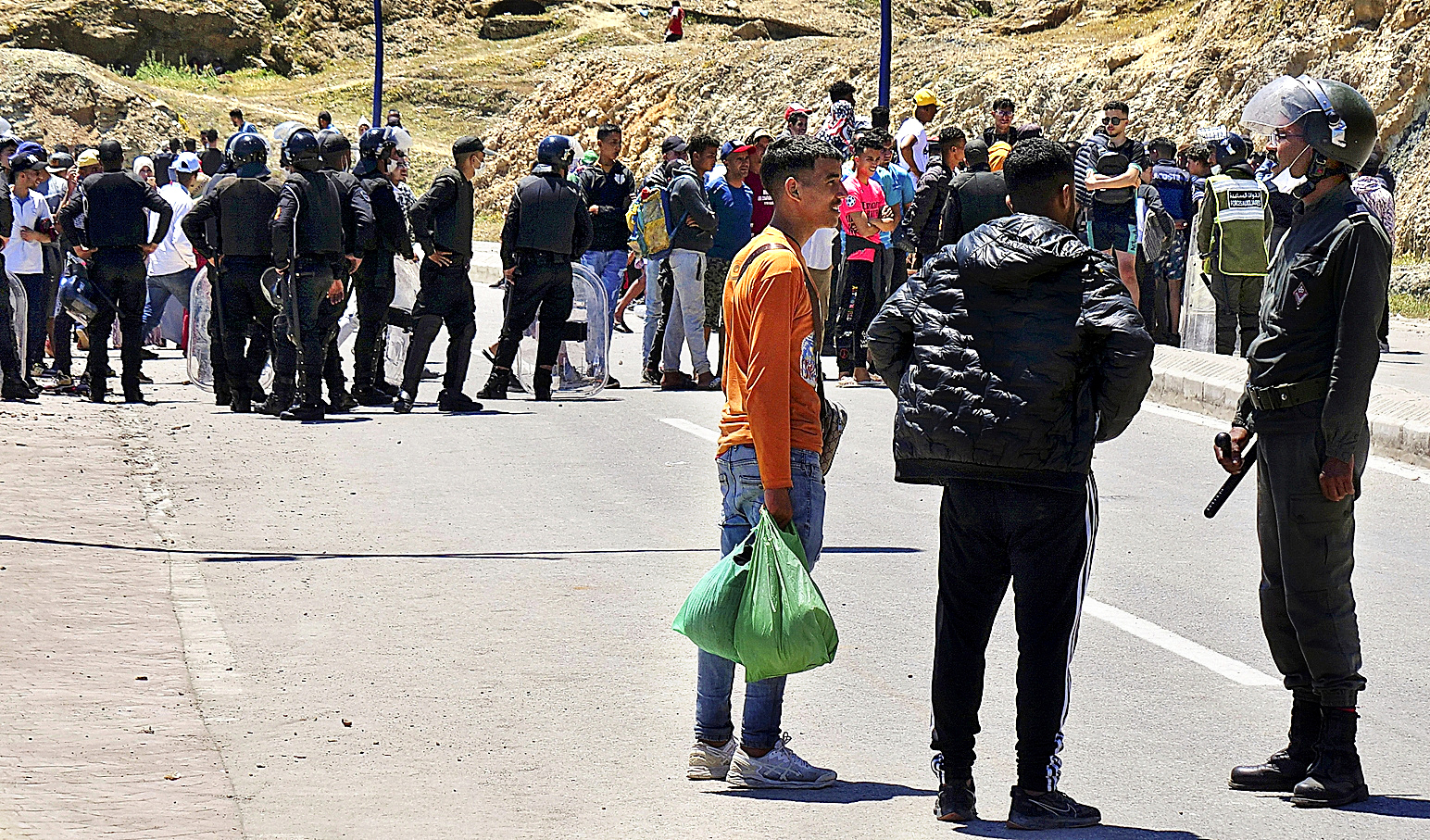 Un polica marroqu conversa ayer con dos migrantes en Castillejos.
