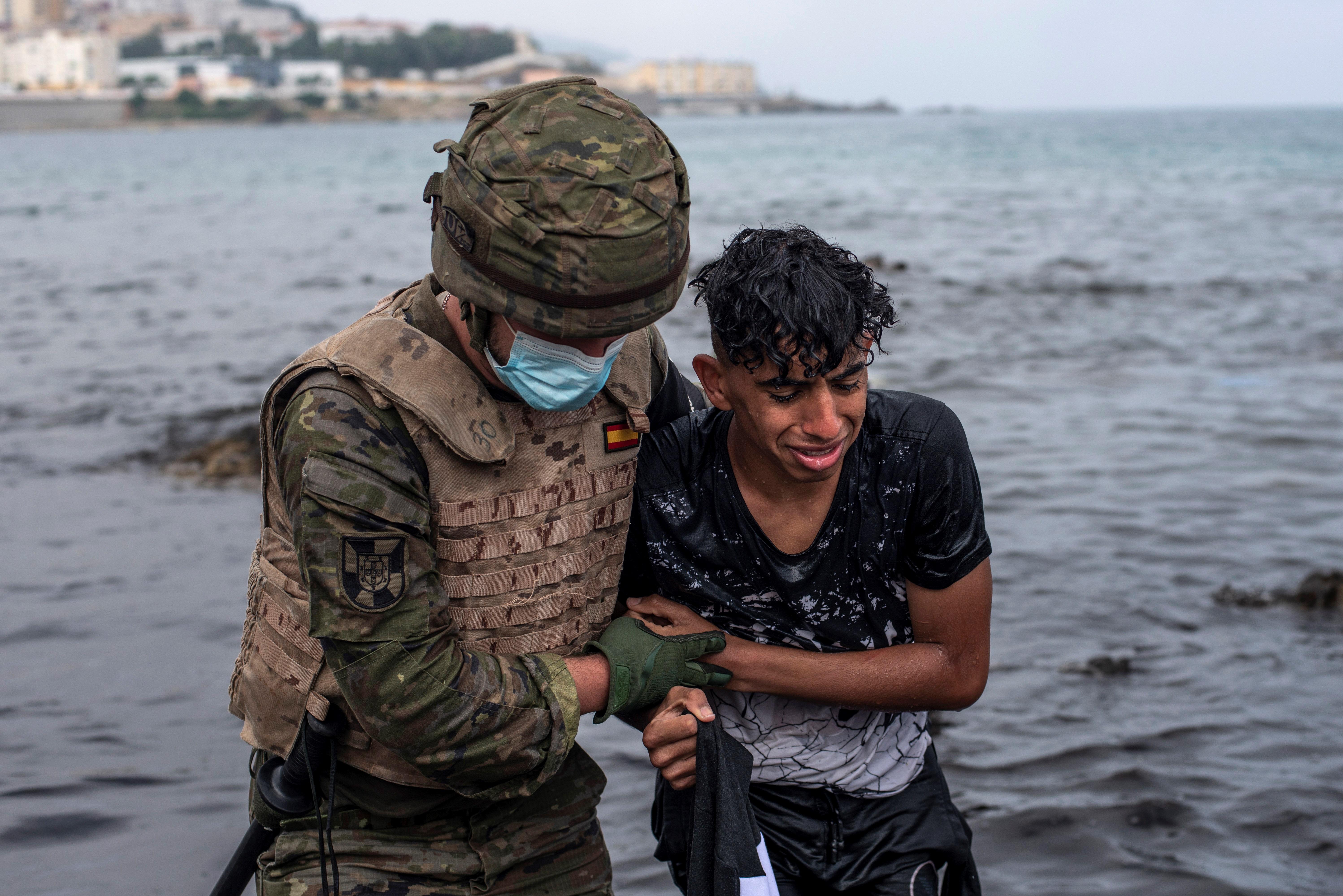 Un soldado del Ejrcito ayuda a un inmigrante a salir del agua en la playa de El Tarajal este mircoles.
