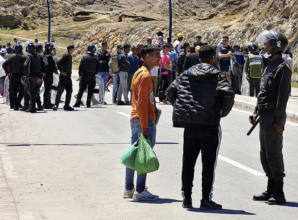 Un policía marroquí junto a un grupo de inmigrantes en Fnideq (Castillejos).