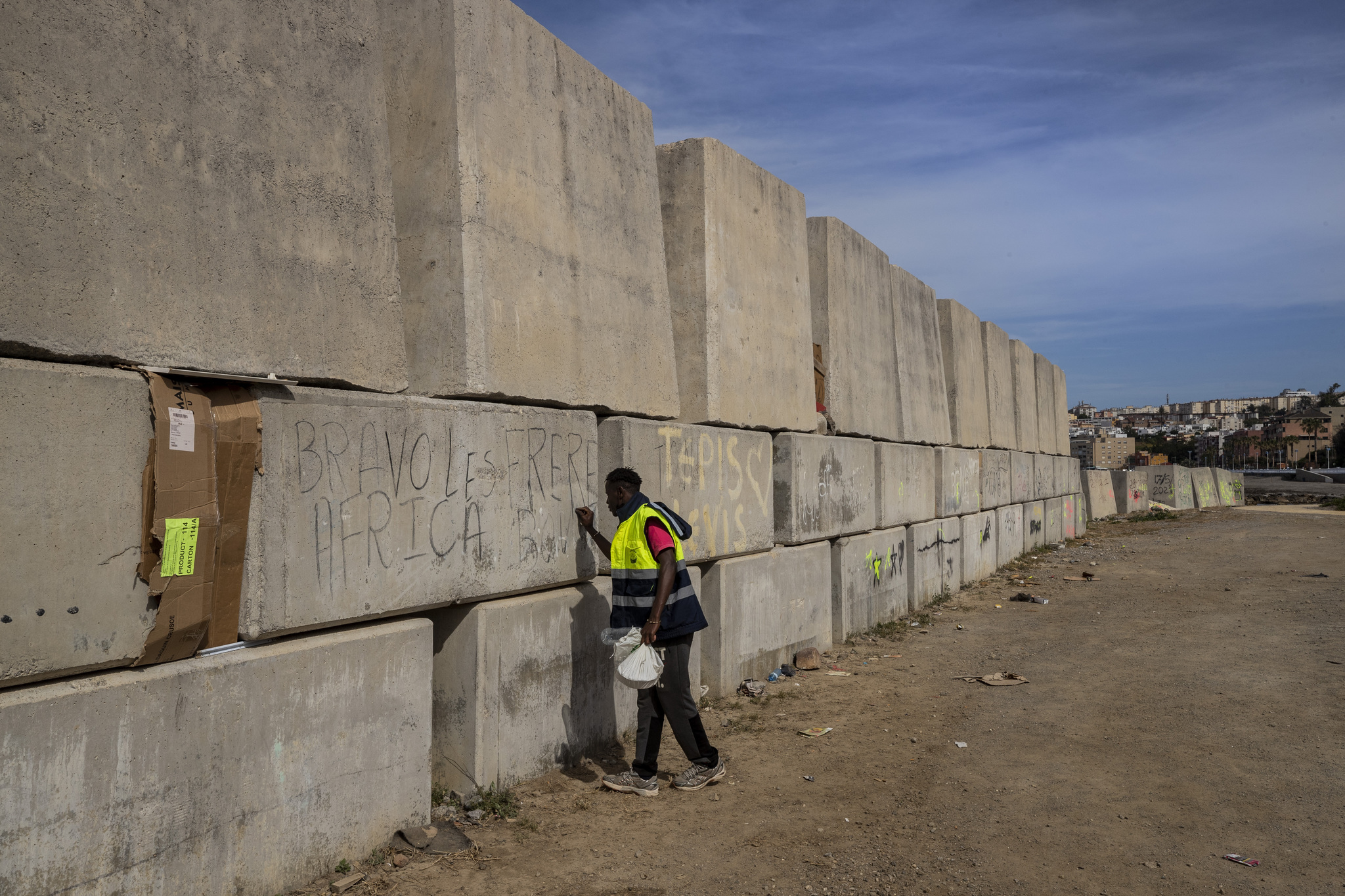 Un migrante subsahariano escribe su nombre en el espigón del enclave español de Ceuta.
