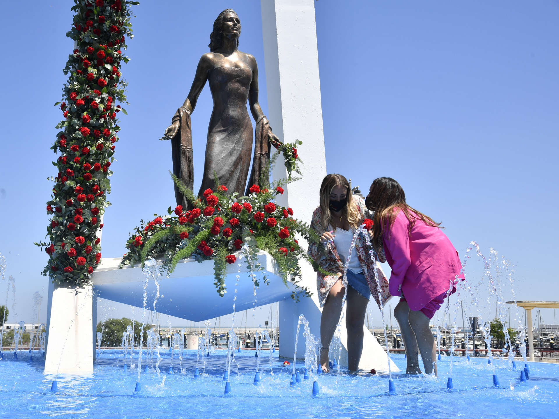 Roco Flores y Gloria Camila colocan unos claveles en el monumento de Roco Jurado.