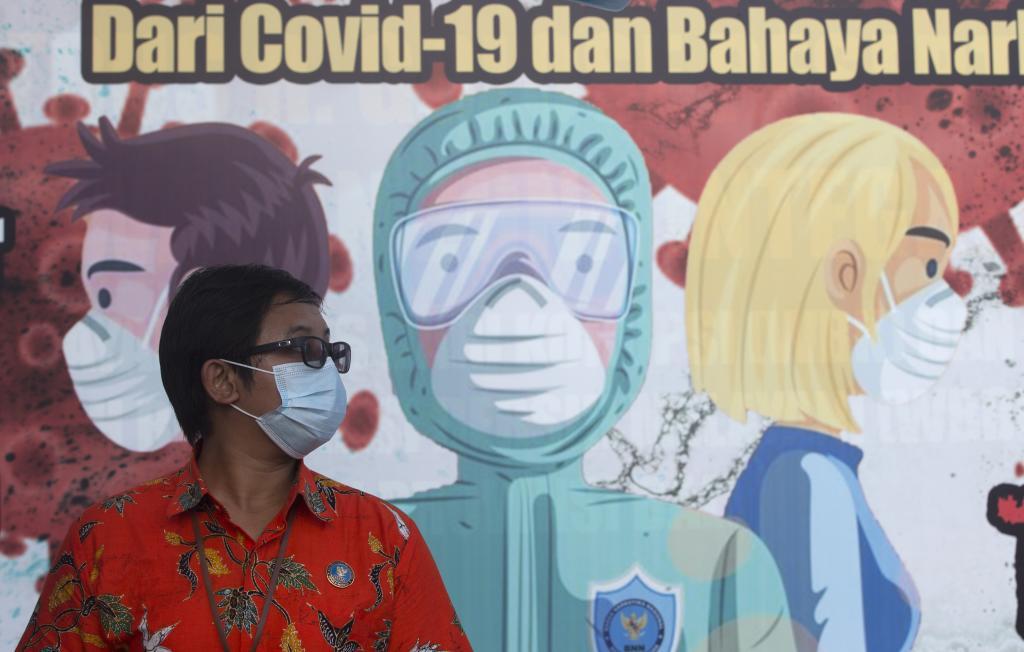 Una mujer con mascarilla para el coronavirus frente a un mural.