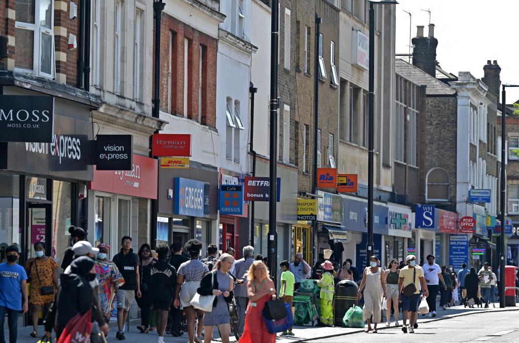 Peatones, unos con mascarilla y otros sin ella, pasean frente a las tiendas en Hounslow, al oeste de Londres.