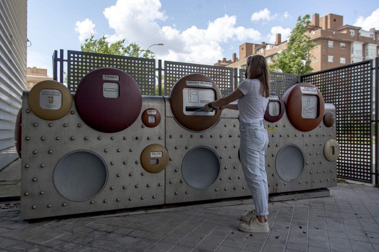 Una joven recicla en un punto limpio de Madrid