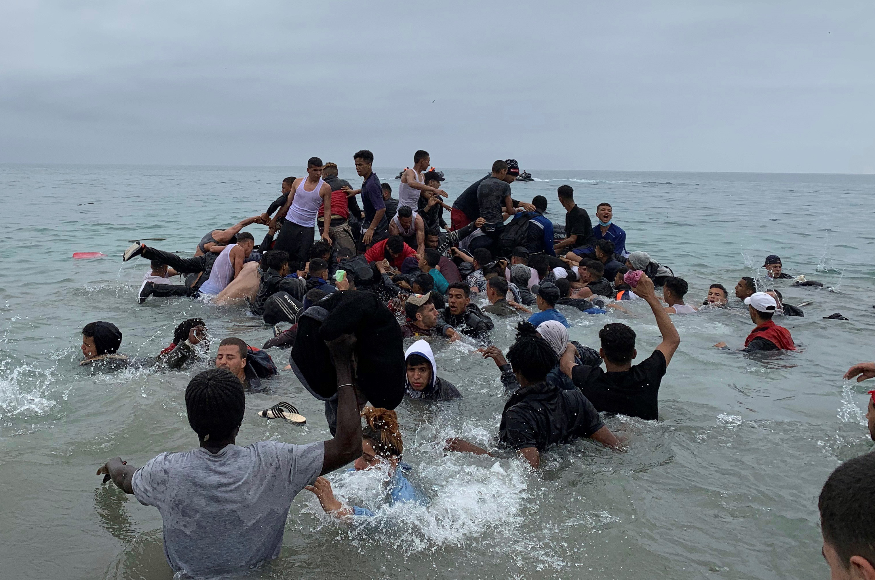 Un grupo de personas se hacen con una embarcacin de las autoridades marroques en la playa de la localidad de Fnideq (Castillejos) para cruzar los espigones de  Ceuta.