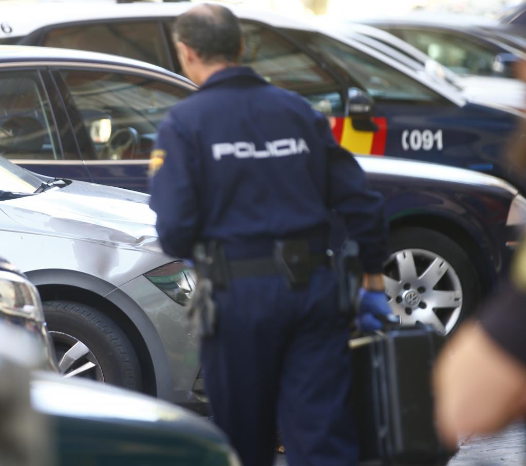 Un polica nacional junto a un coche patrulla.