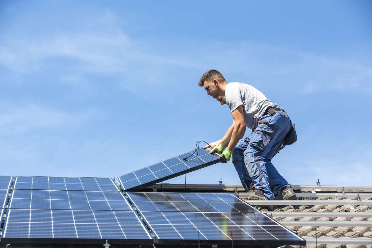 Dos operarios trabajan en la instalacin de placas solares en un tejado de una vivienda.