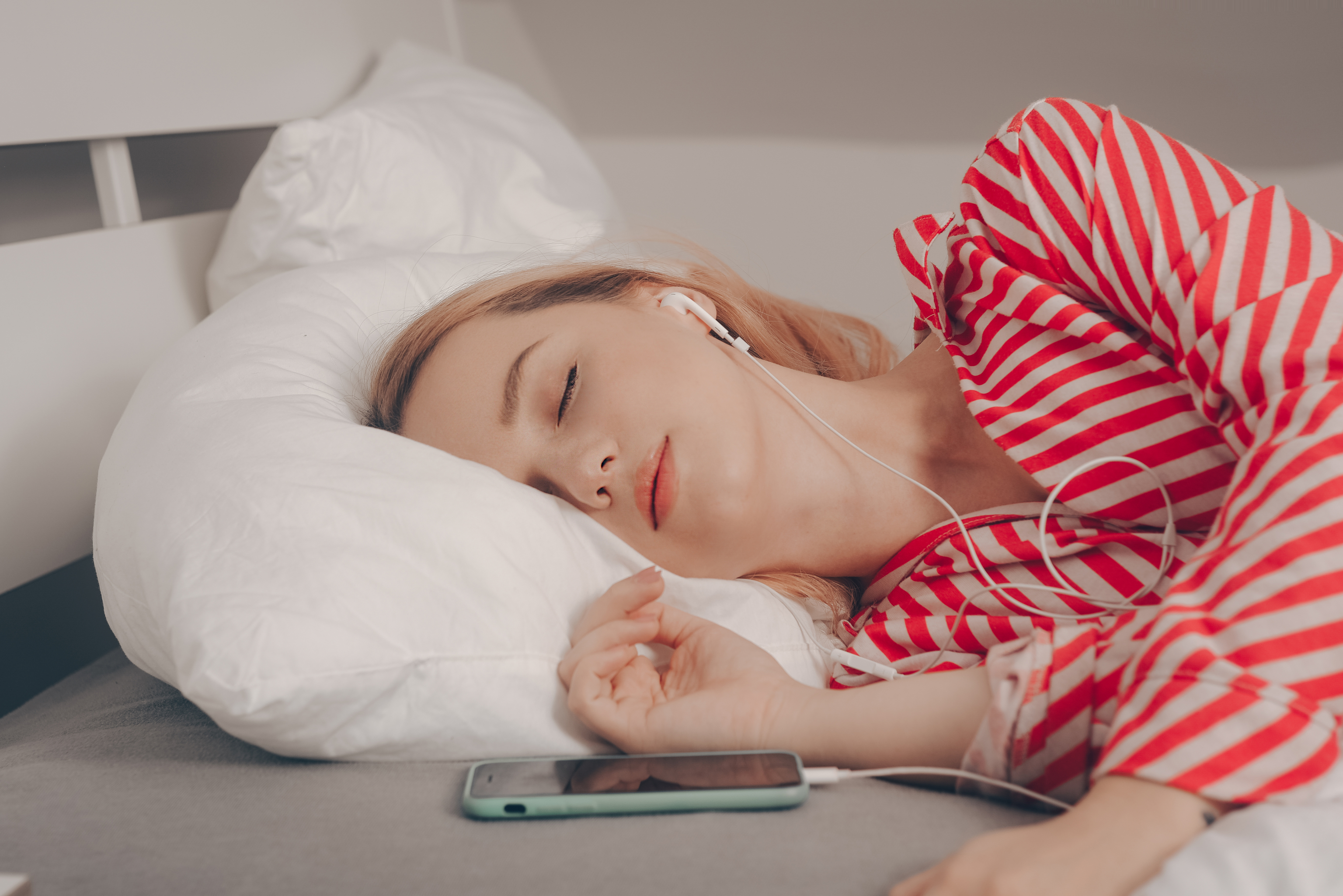 Una mujer duerme con auriculares.