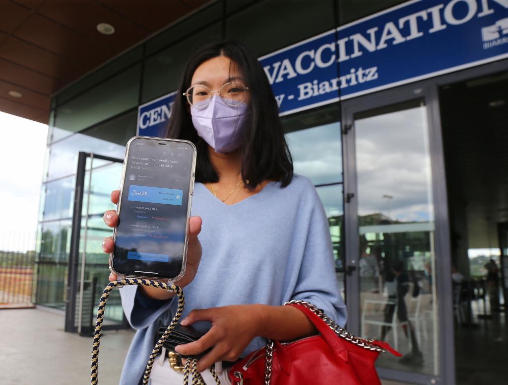 Una joven guipuzcoana muestra su citacin para vacunarse junto a las puertas del centro sanitario de Biarritz.