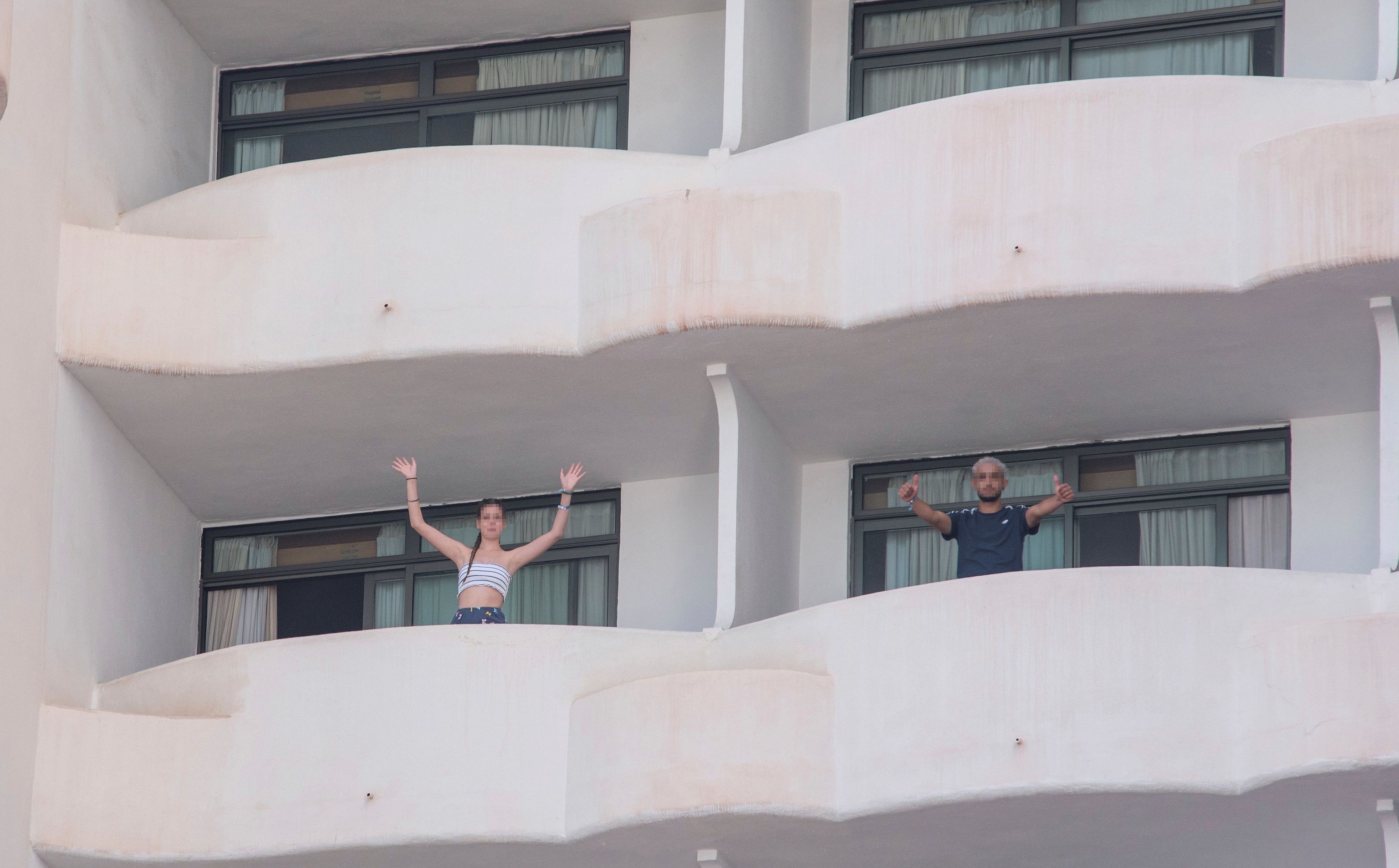 Dos jvenes que permanecen en aislamiento en el hotel Palma Bellver de Palma saludan desde los balcones.