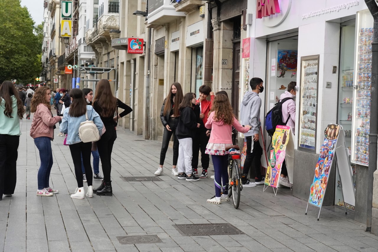 Varios adolescentes hacen cola para comprar en una tienda de golosinas en el centro de Vitoria.