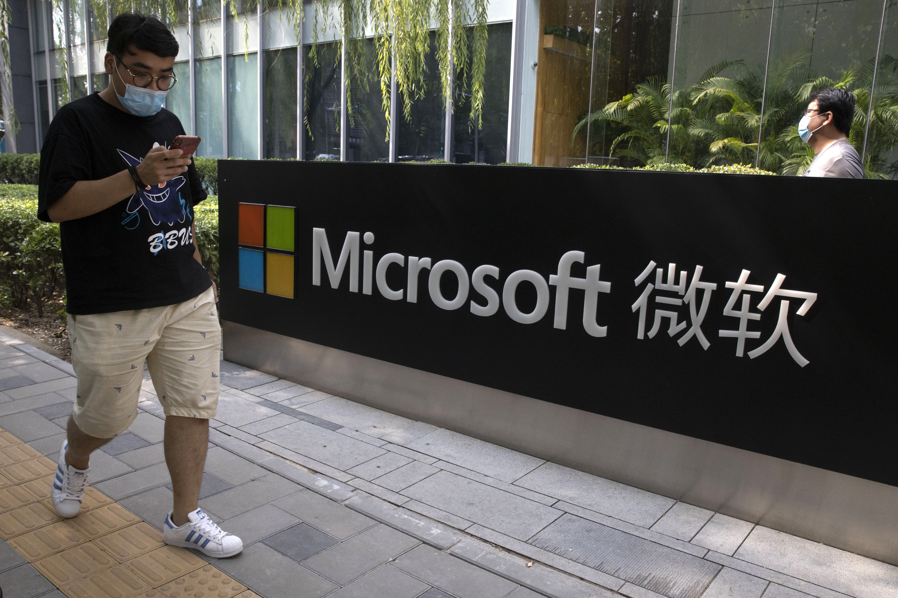 Un hombre consulta su smartphone junto a una oficina de Microsoft en Pekín.