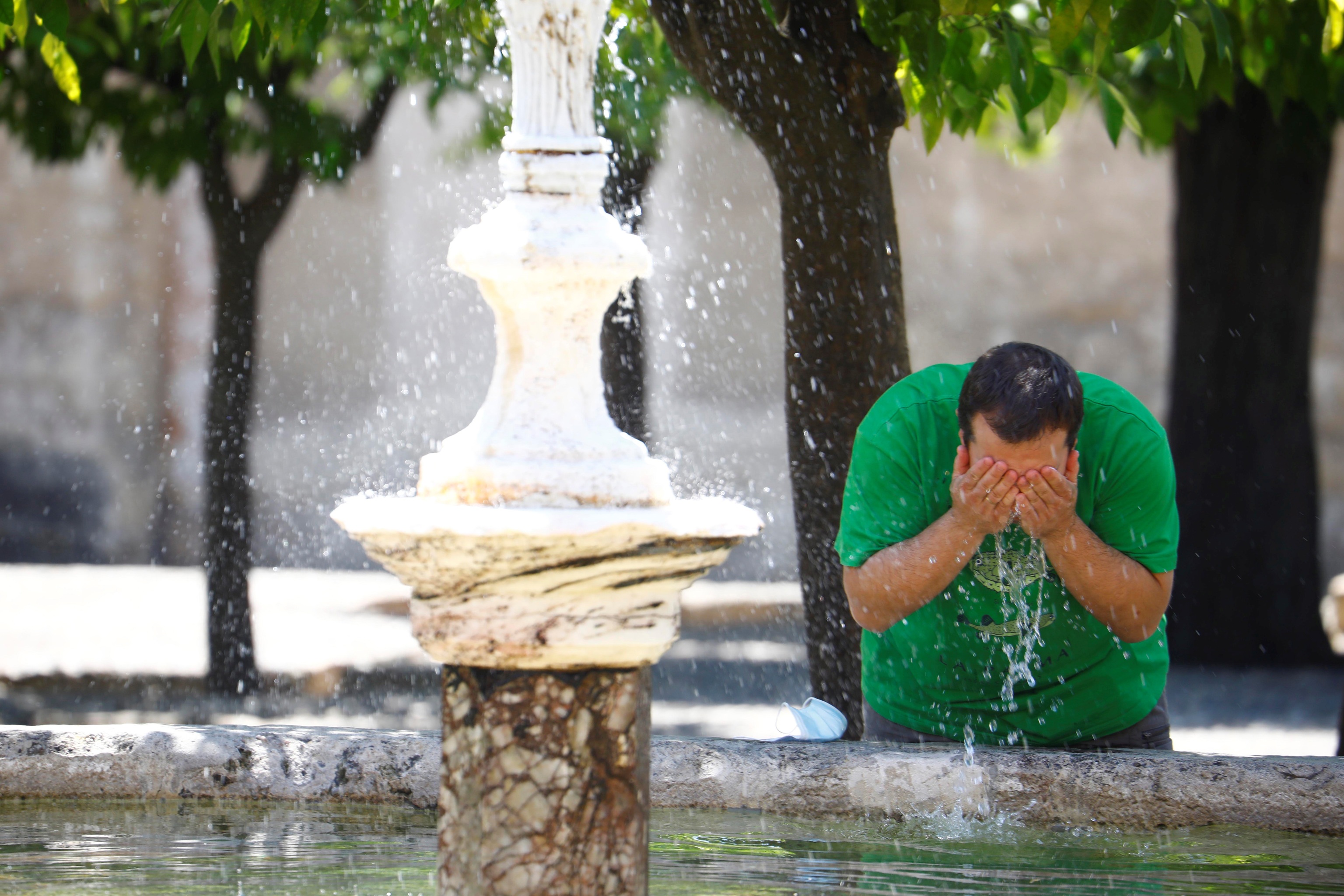 Un hombre se refresca en la fuente de los naranjos de la Mezquita - Catedral de Crdoba