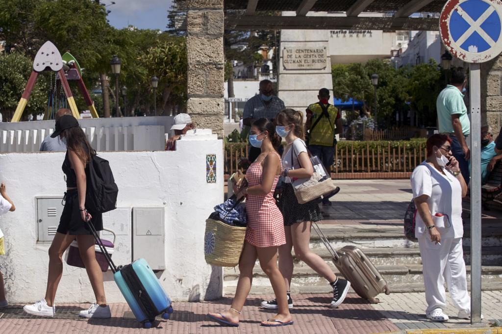 Turistas con mascarillas y maletas en una calle cntrica de Tarifa (Cdiz).