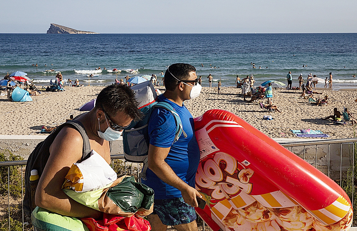 Turistas cargados con aperos de playa en Benidorm.