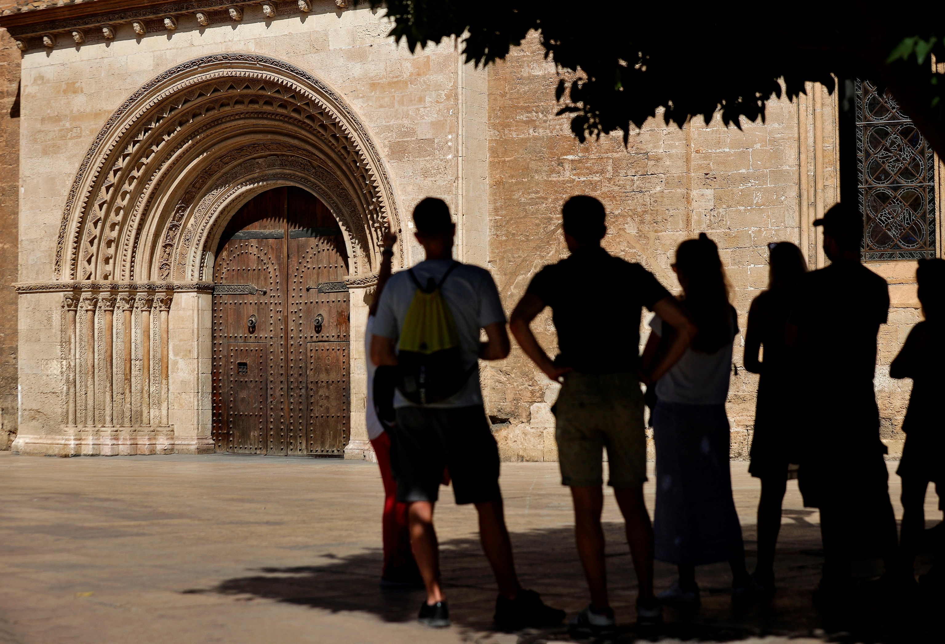 Jóvenes se refugian del sol en la Plaza de la Virgen de Valencia.