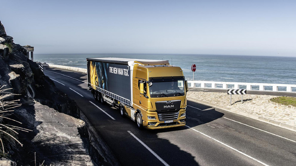 Un profesional del transporte conduce un camión por una carretera de la costa.