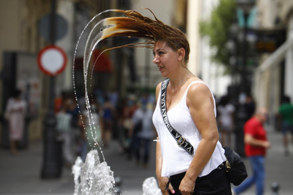 Una mujer se refresca en una fuente del centro de Crdoba.