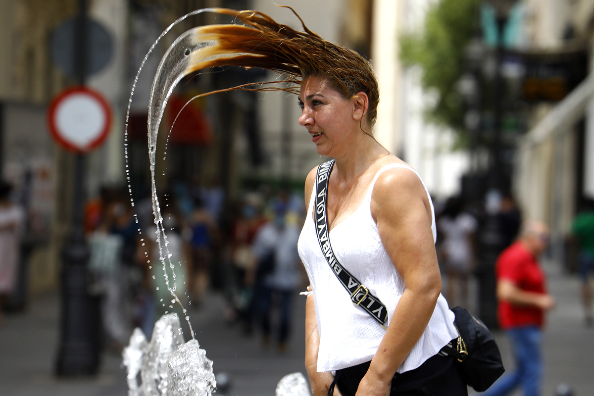 Una mujer se refresca en una fuente de Crdoba.