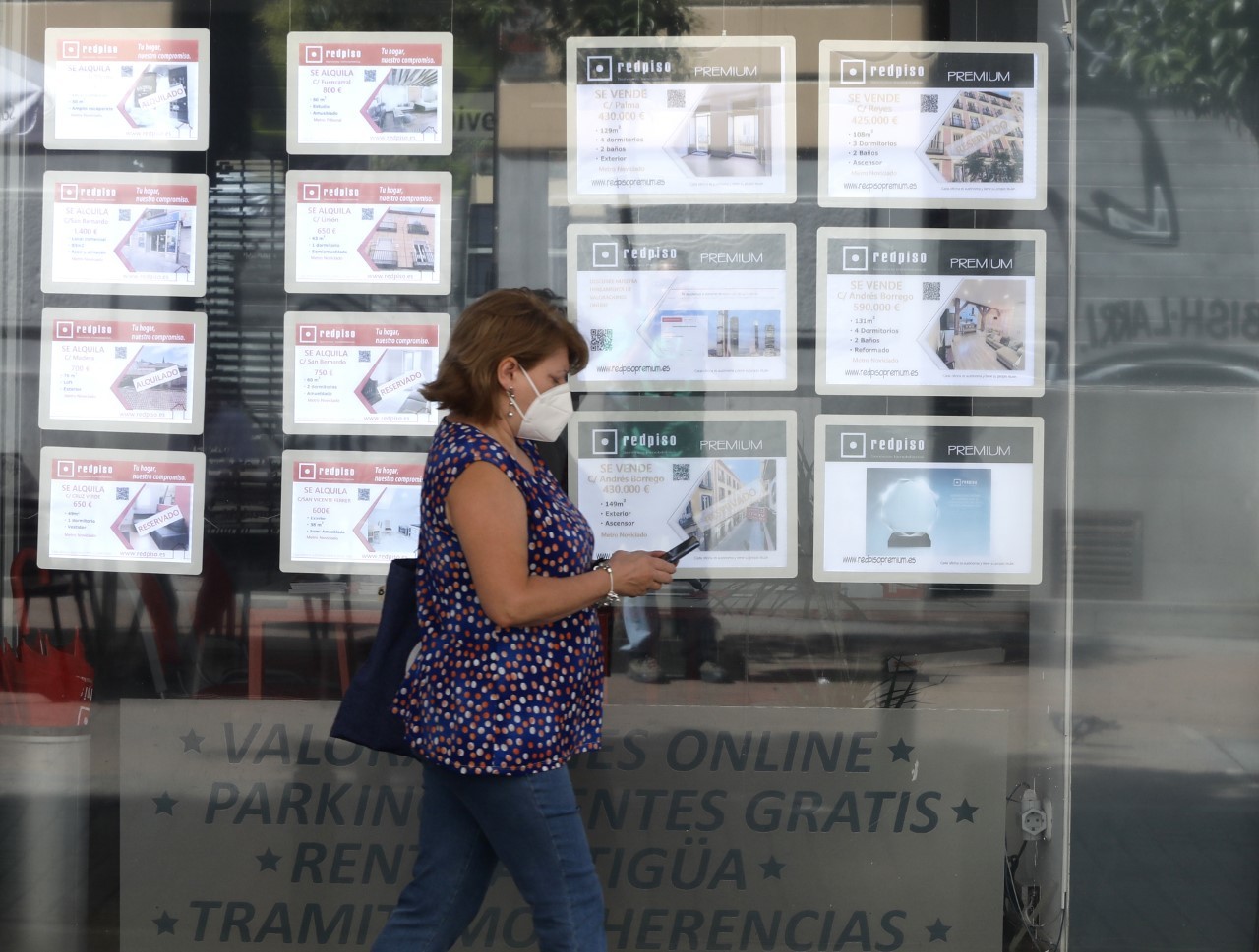 Una mujer pasa ante los anuncios de una inmobiliaria en Madrid.