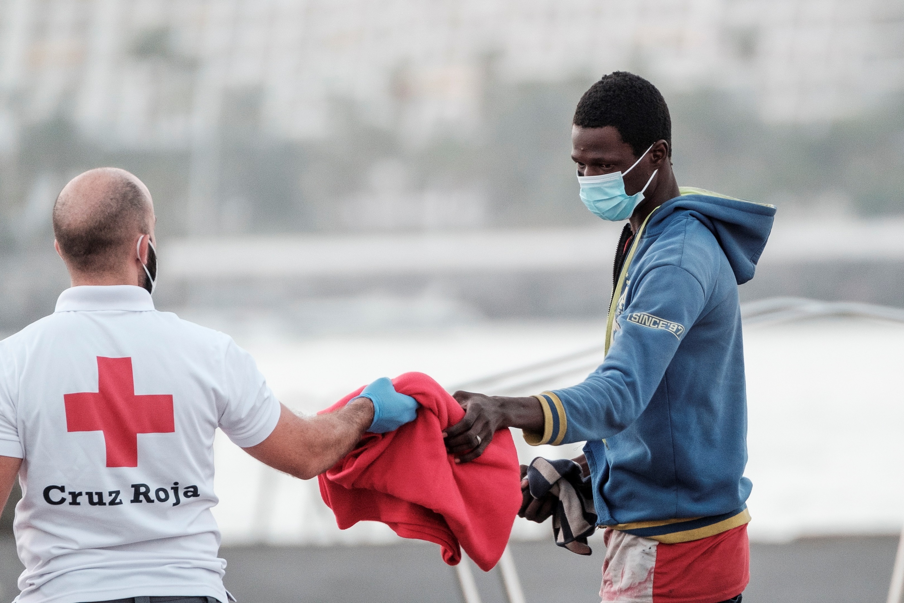 Un miembro de la Cruz Roja facilita una manta a un inmigrante, este jueves, en Gran Canaria.