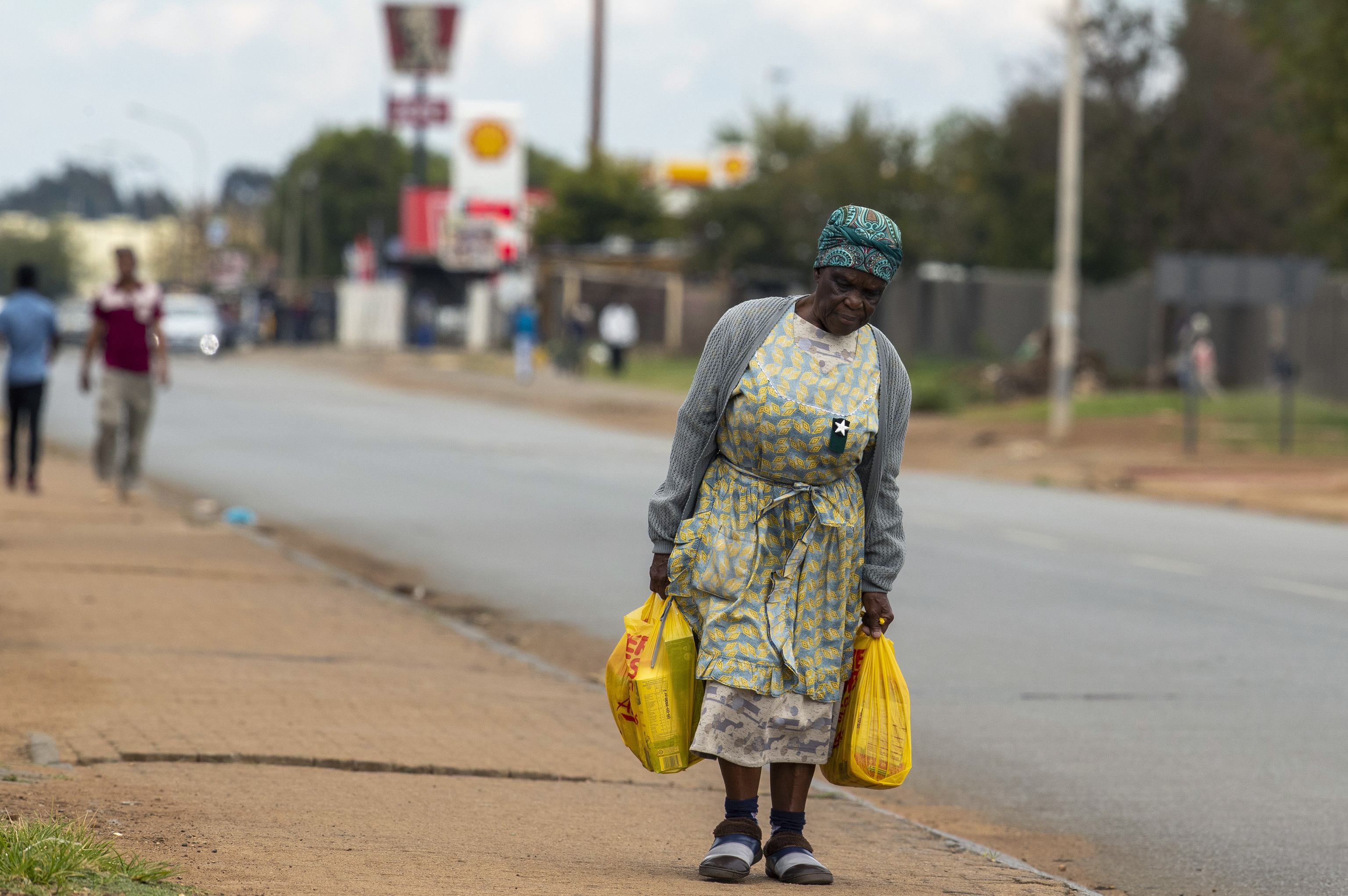 Una mujer regresa a su casa en Thokoza, al este de Johanesburgo, en Sudáfrica, con bolsas de la compra.