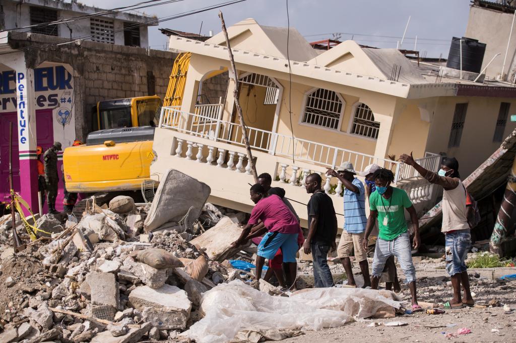 Varias personas trabajan en un edificio derruido en Les Cayes (Haití).