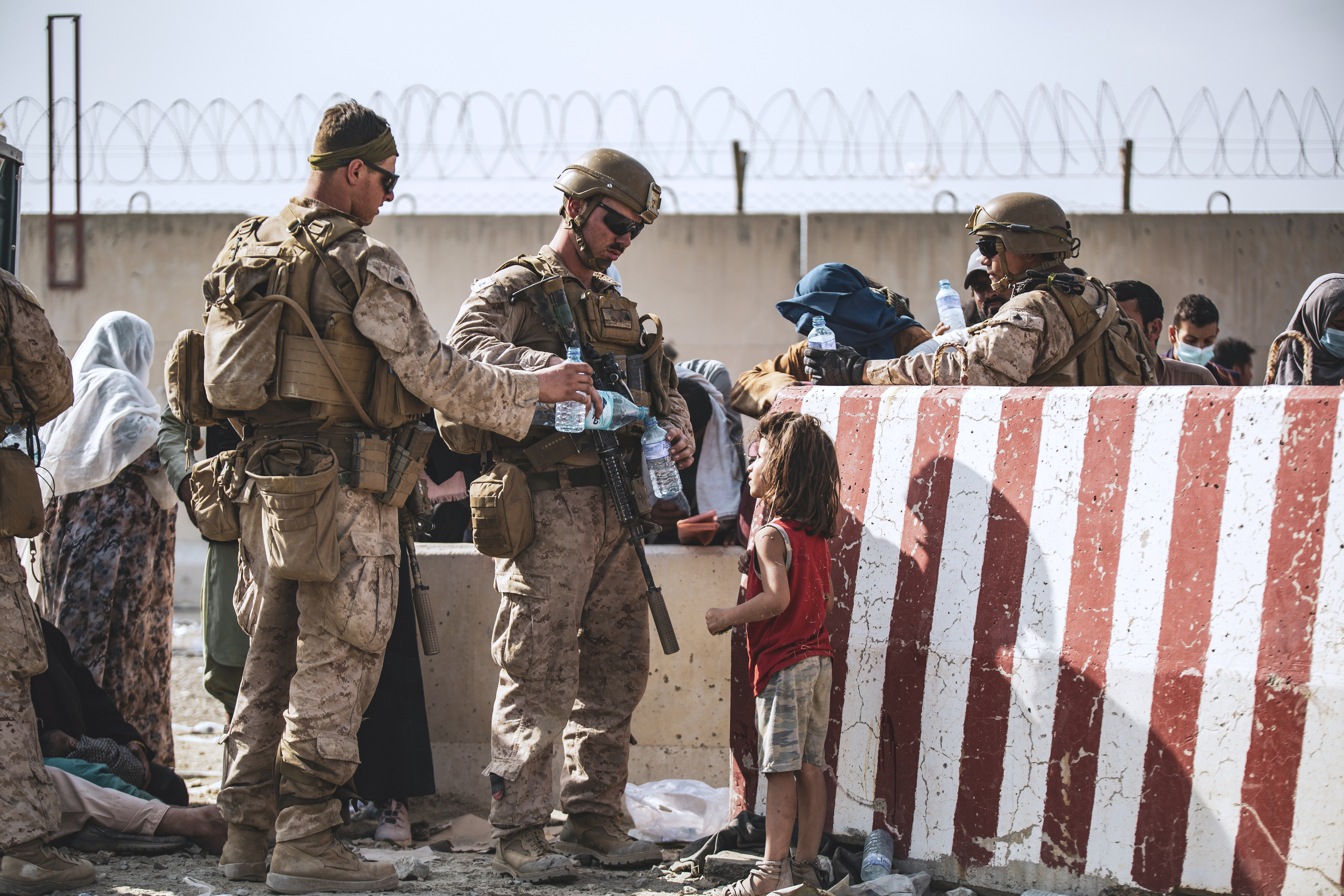 Un grupo de marines del ejército de EEUU dan agua a una niña en el aeropuerto de Kabul.