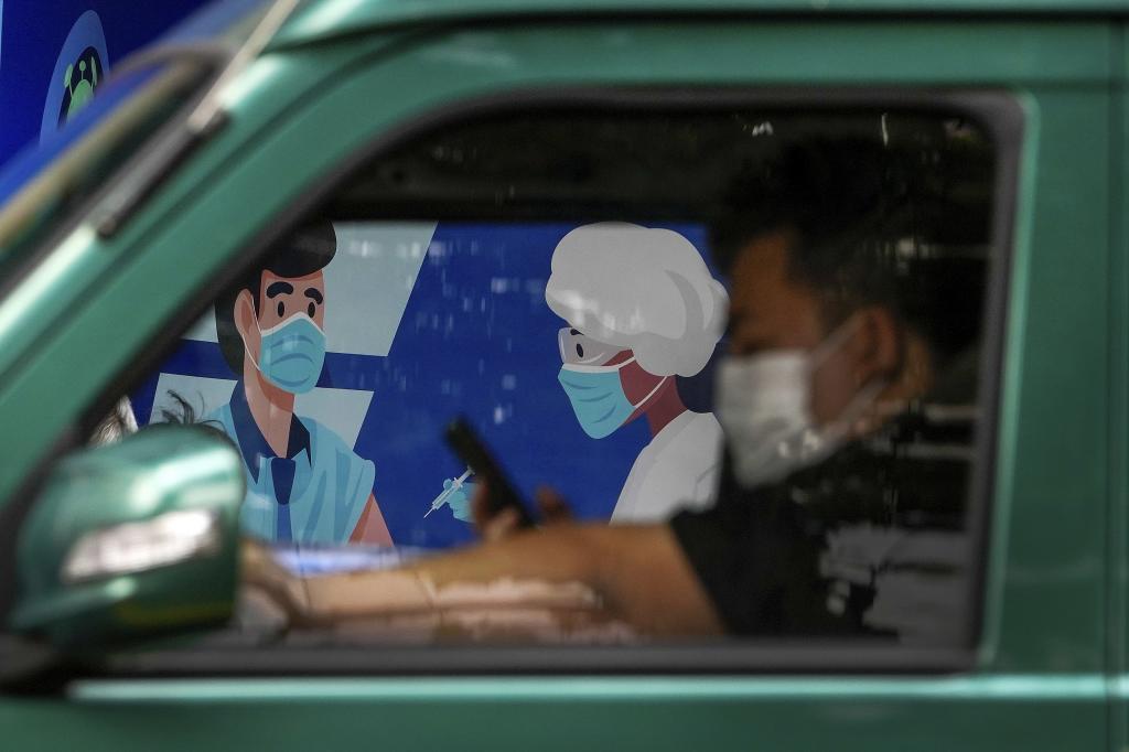 Un hombre con mascarilla en su coche en Shanghai.