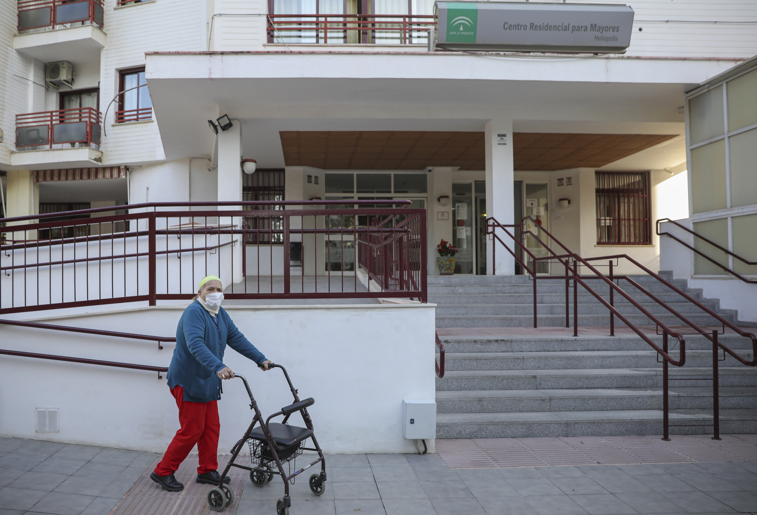 Una persona camina con la ayuda de un andador a las puertas de una residencia de Sevilla.