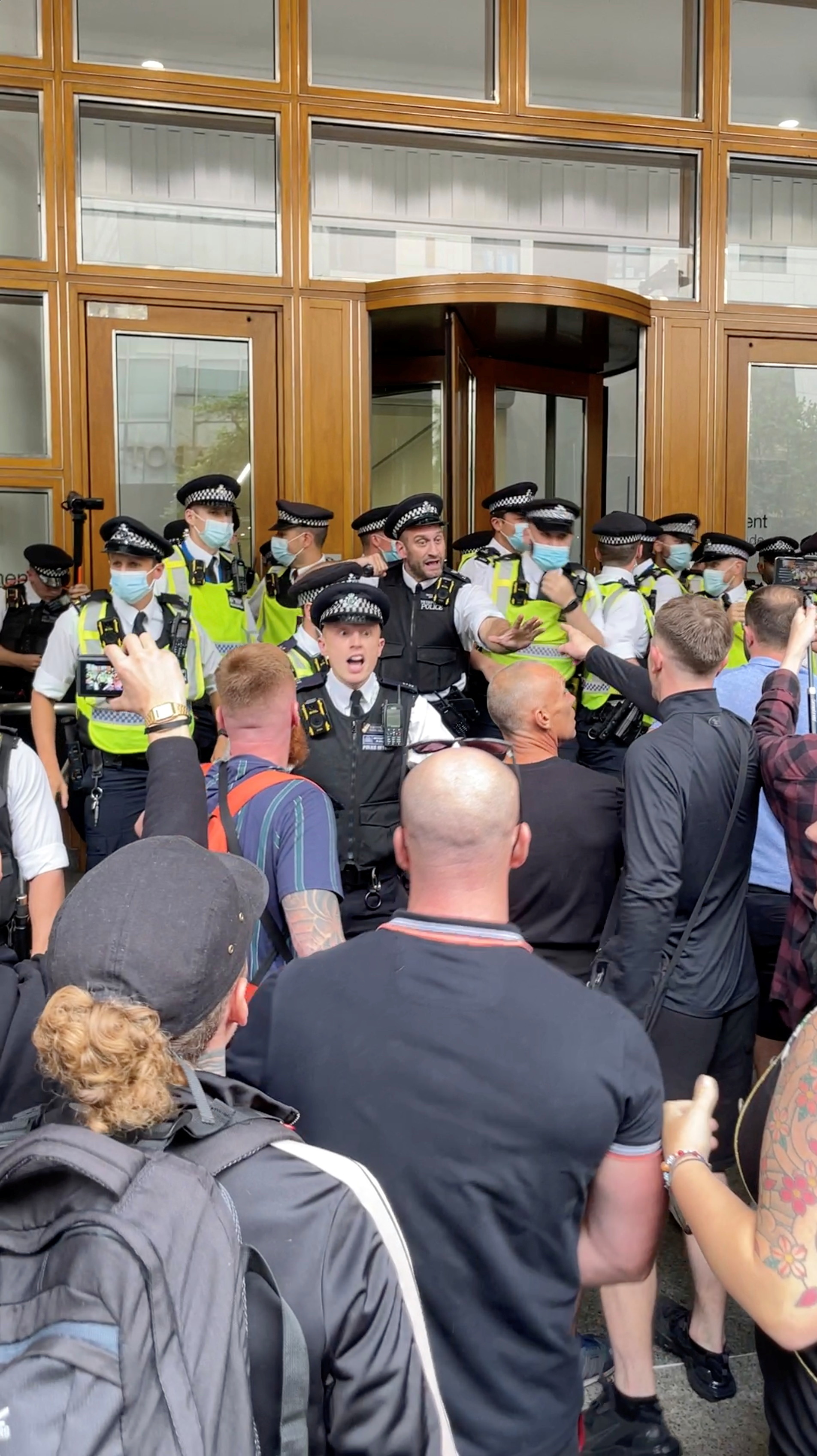 Policas  y manifestantes se enfrentan  ante la sede de la MHRA en Canary Wharf.