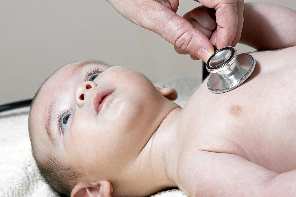 Un pediatra auscultando el pecho a un bebé.