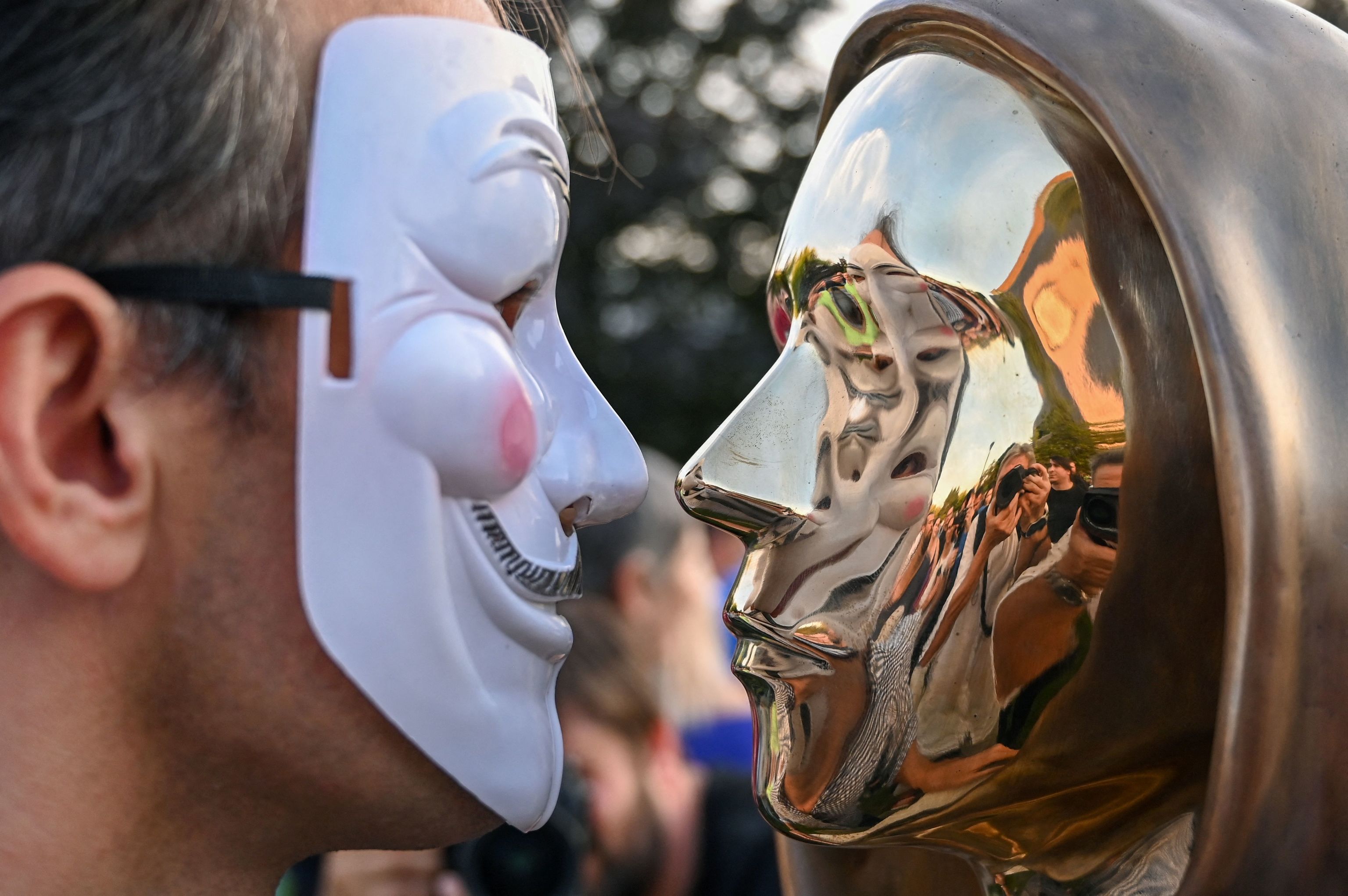 Un asitente con una mscara de Guy Fawkes posa delante de la estatua de Satoshi Nakamoto, el misterioso inventor de la moneda virtual bitcoin, tras su inauguracin en el parque Graphisoft de Budapest, el 16 de septiembre de 2021.