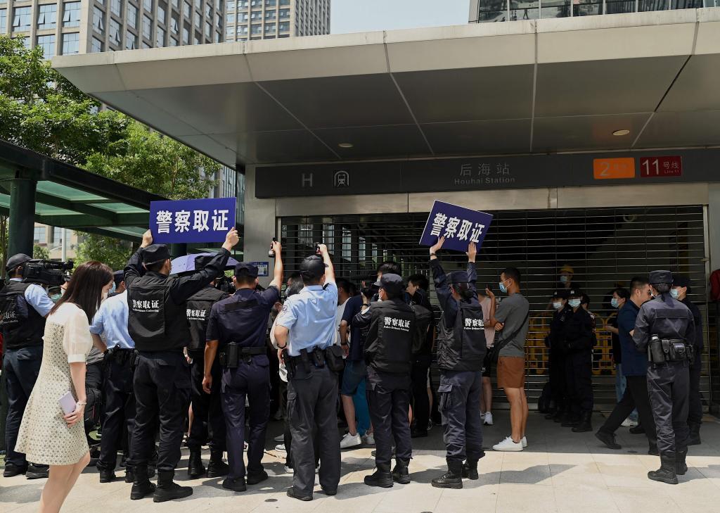 La polica observa a unos manifestantes en la sede de Evergrande en la ciudad de Shenzhen