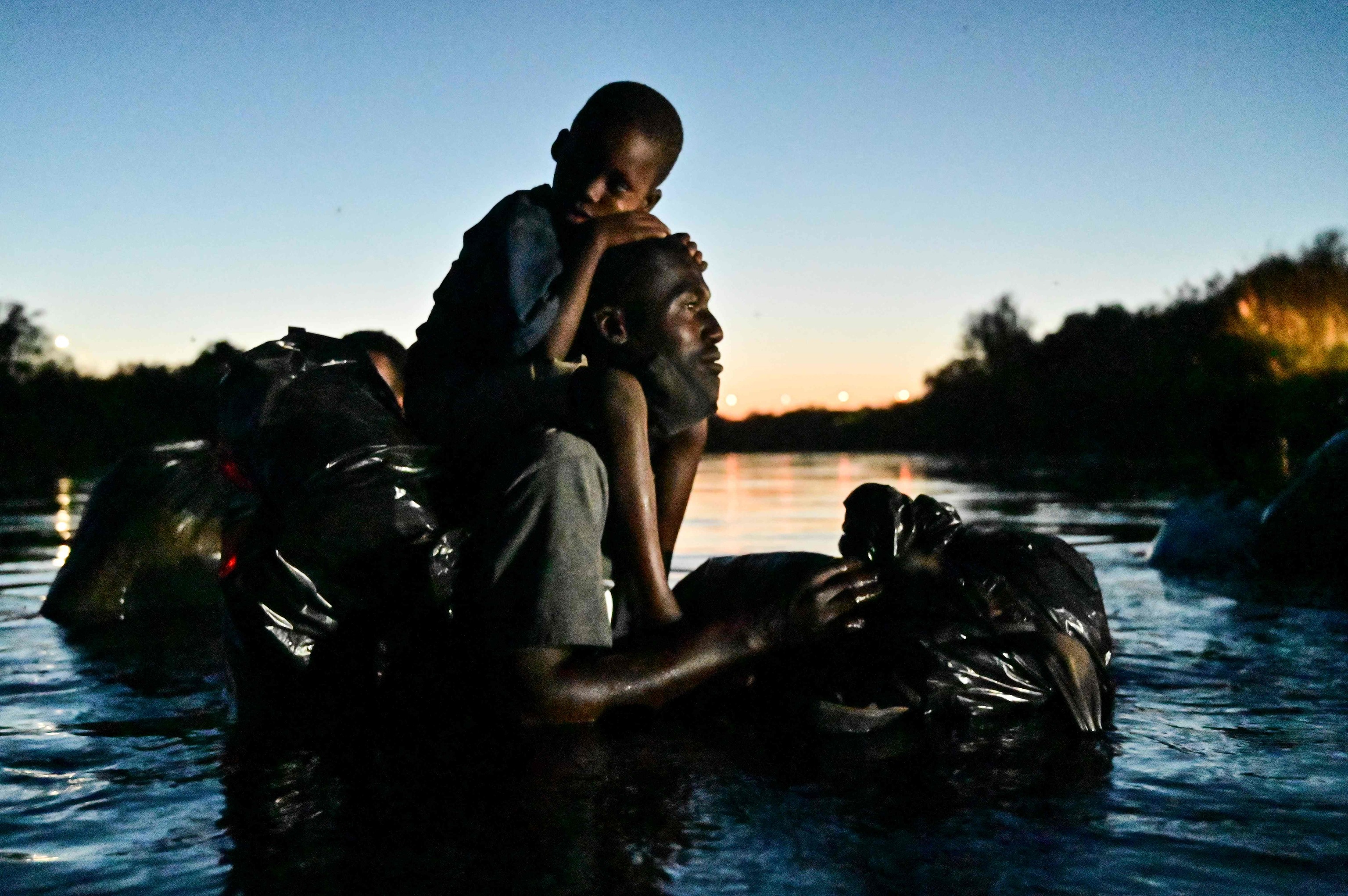 Un hombre carga con su hijo en brazos al cruzar Rio Grande para llega a EEUU.