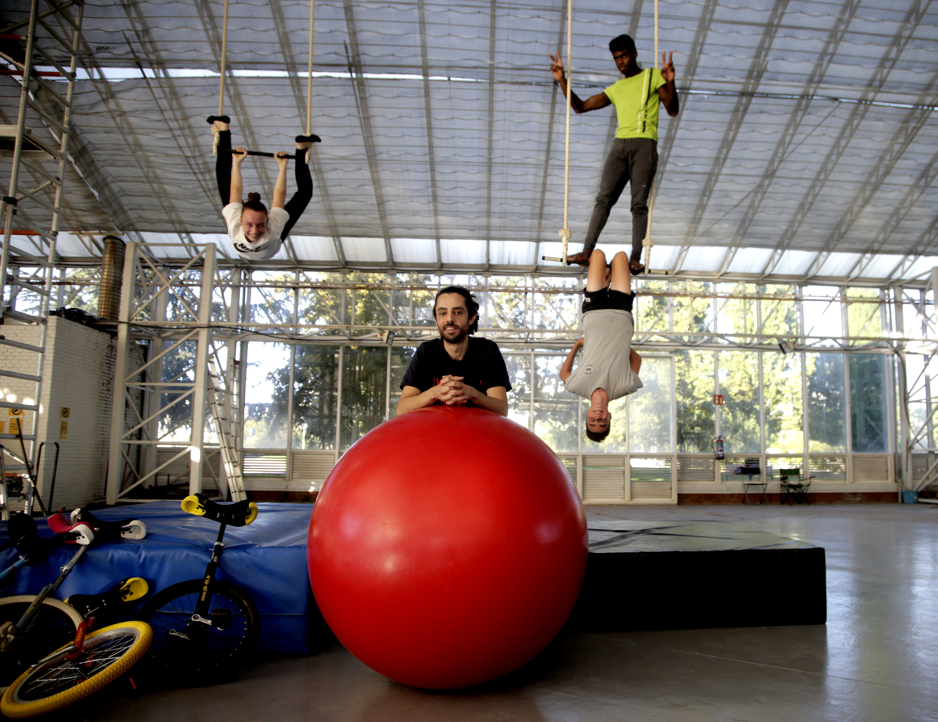 Tres alumnos practican acrobacias con su profesor en la escuela de circo El Invernadero.