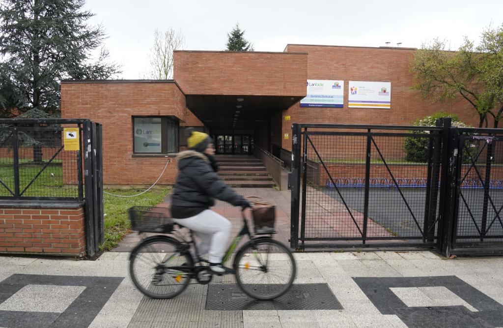 Una joven circula con su bicicleta junto al acceso a la oficina de Lanbide deL barrio de Txagorritxu de Vitoria.