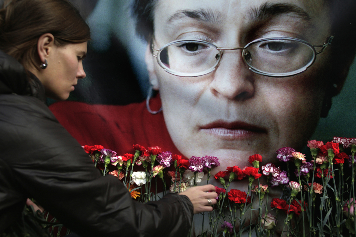 Una mujer coloca flores ante un retrato de Anna Politkovskaya.