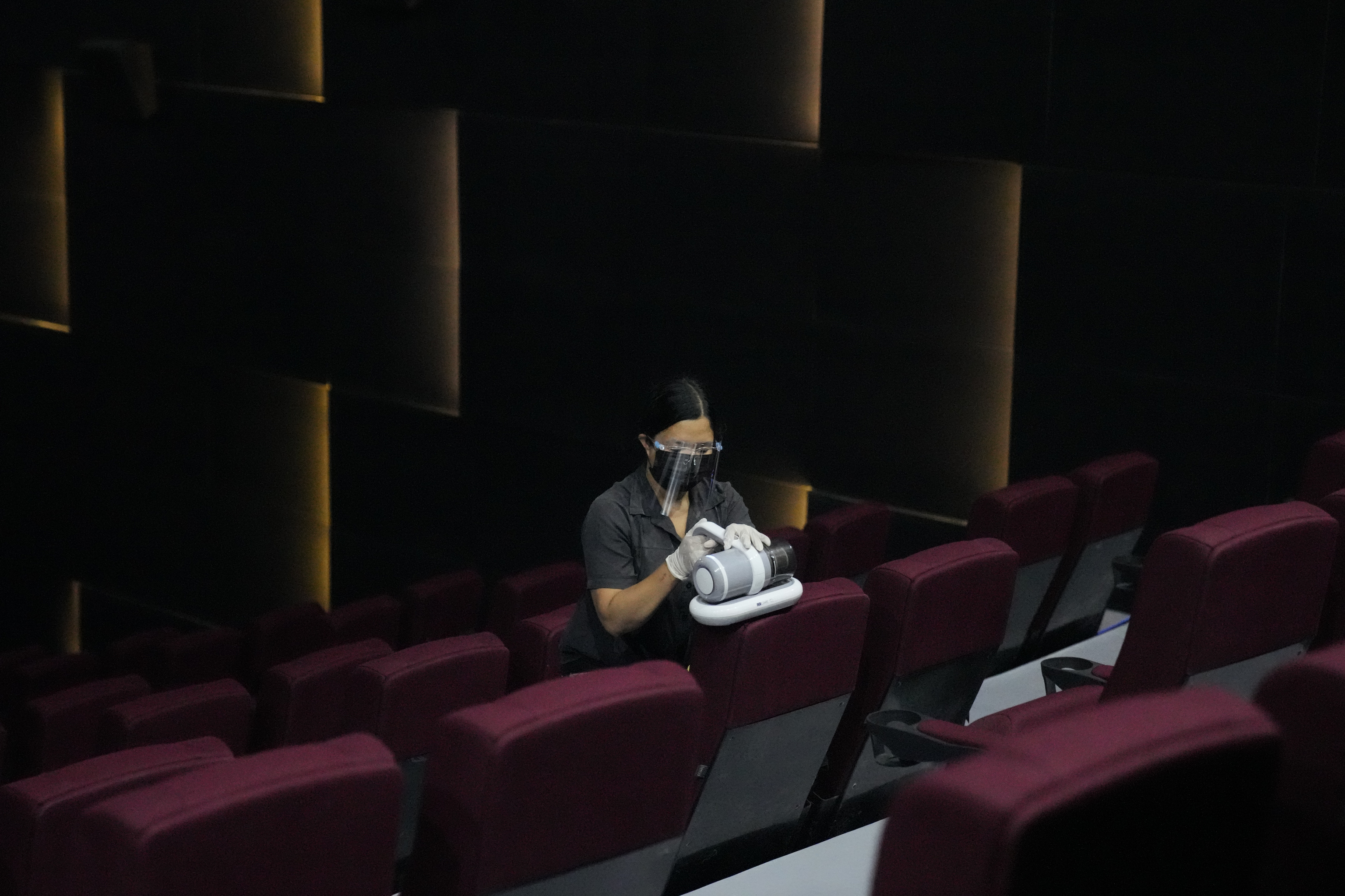 Una mujer desinfecta una sala de cine.