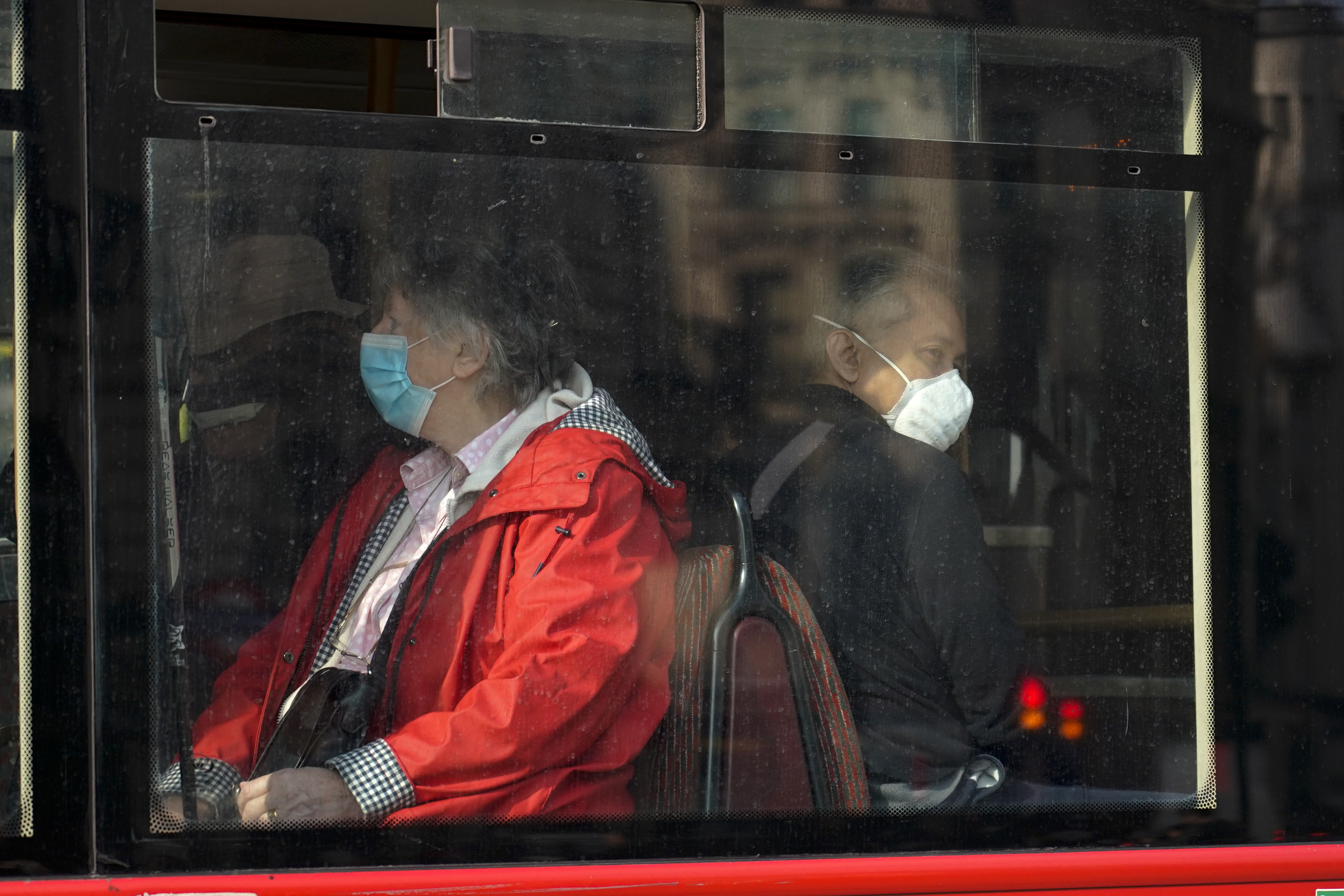 Dos personas llevan mascarilla mientras viajan en bus.
