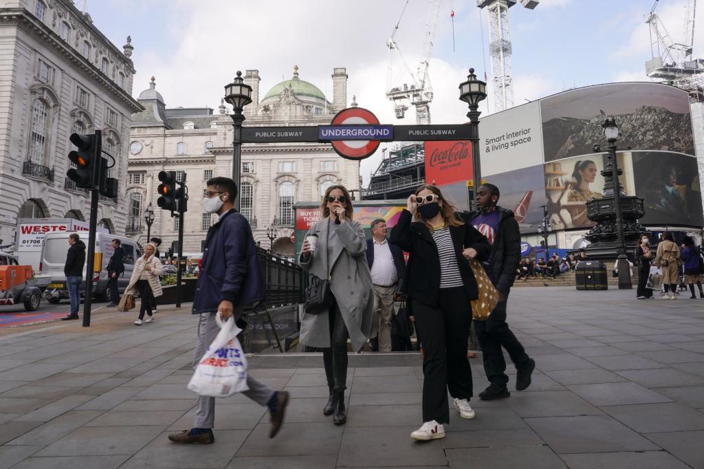 Personas con y sin mascarilla a la salida de la estación de metro Piccadilly Circus, en Londres.