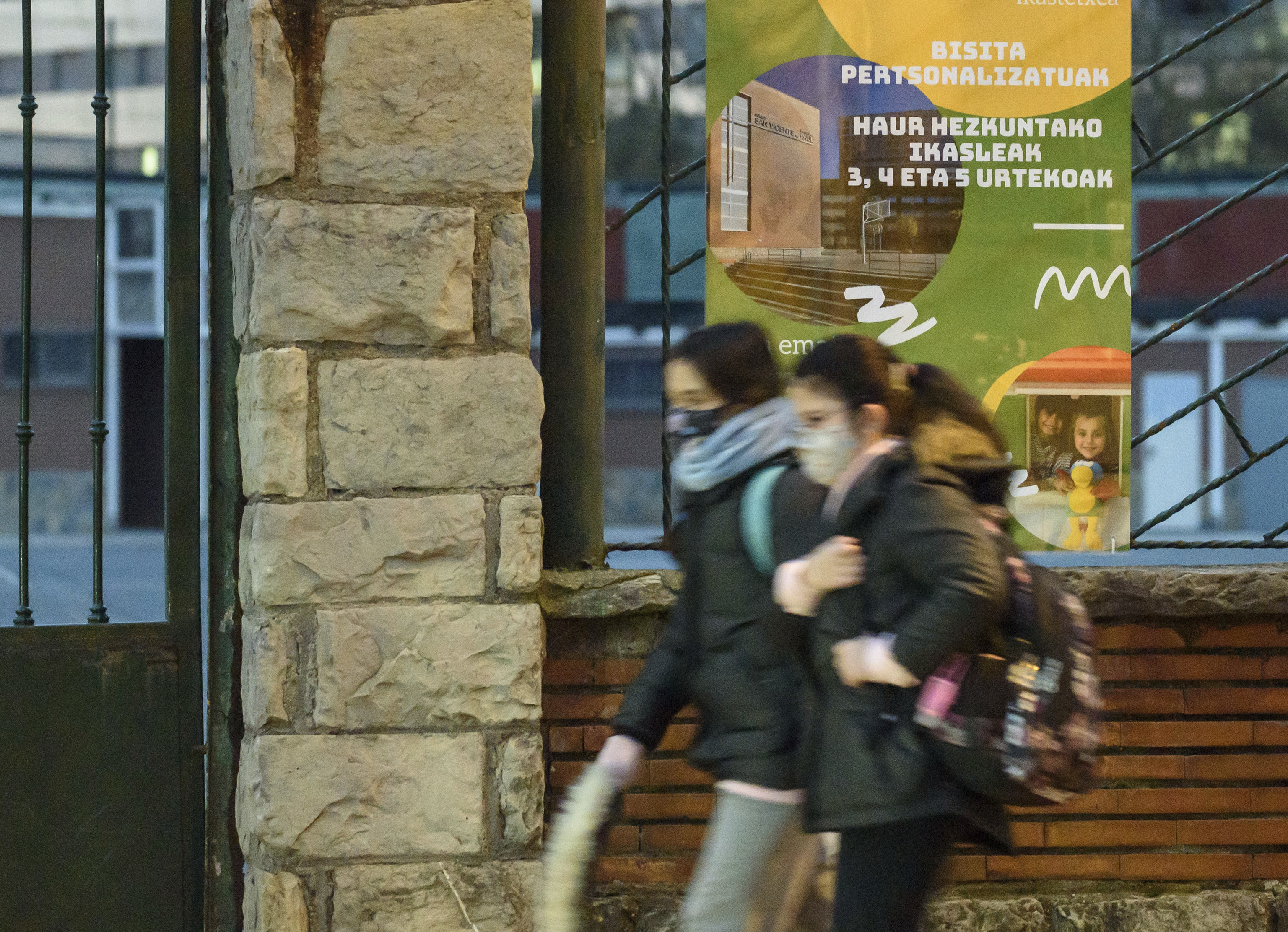 Dos jóvenes caminan junto a un cartel en euskera en un centro educativo de Vizcaya.